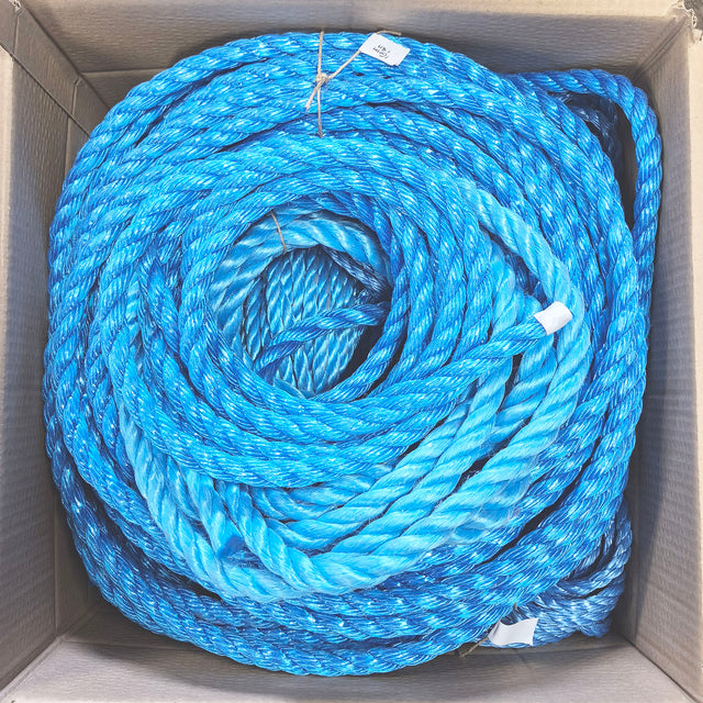 Coils of bright blue and light blue twisted rope stored inside a cardboard box, viewed from above.
