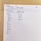 A handwritten size chart on a white sheet of paper titled 'Poly Blue' with measurements for sizes 16mm and 20mm, placed on a brown kraft paper background.