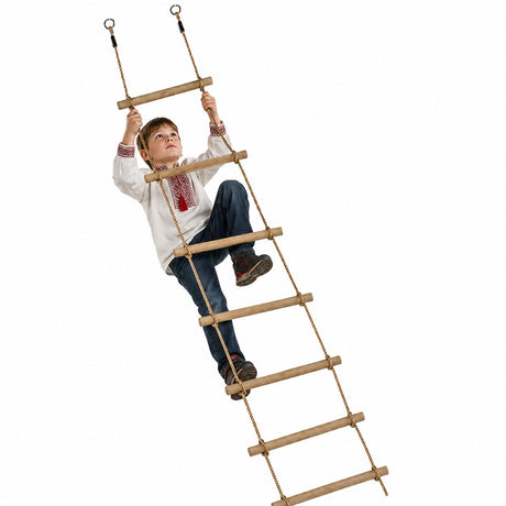 A young boy in a white embroidered shirt and blue jeans is climbing a wooden rope ladder with wooden rungs against a solid white background.