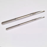 Two metal Selma needles on a white background