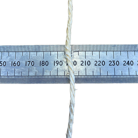 A close-up of a sisal rope, running vertically down the centre of a metal ruler on a white background, to show thickness.